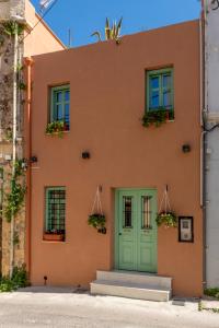 a orange building with a green door and windows at Sartori Concept Hotel in Heraklio Town