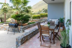 een patio met een tafel en stoelen en een stenen muur bij Eleanna's House - 400m From the Beach in Rethimnon