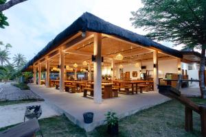 un restaurante con mesas de madera y techo en Bintan Exotica Resort en Berakit