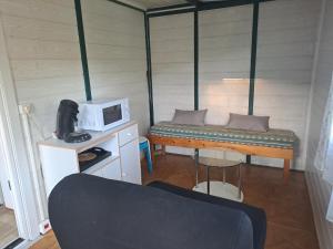 Habitación pequeña con cama y microondas. en Chalet pour 5 personnes équipé sur emplacement privatif dans camping 4 étoiles appartenant et géré par un particulier en Foix