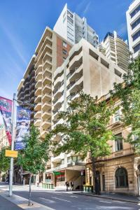 a tall building on a city street with trees at Metro Apartments on King in Sydney