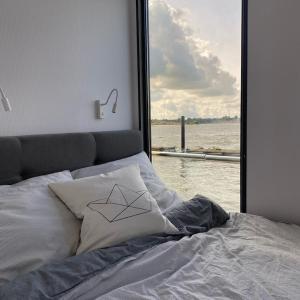 uma cama com uma janela com vista para a água em Hausboot Fjord Schleiliebe mit Biosauna und Dachterrasse in Schleswig em Schleswig
