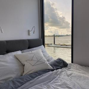 石勒苏益格Hausboot Fjord Schleiliebe mit Biosauna und Dachterrasse in Schleswig的一张带窗户的床铺,俯瞰着水面