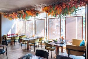 a restaurant with tables and chairs and windows at Valia Hotel Bangkok in Bangkok