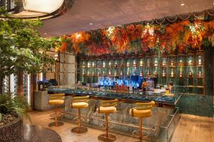a bar with yellow stools and bottles of alcohol at Valia Hotel Bangkok in Bangkok