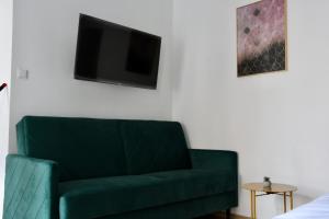 zieloną kanapę w salonie z telewizorem w obiekcie Narutowicza 5 Apartments w mieście Inowrocław