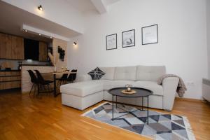 ein Wohnzimmer mit einem weißen Sofa und einem Tisch in der Unterkunft Apartment Cejf Mostar in Mostar