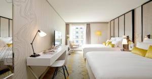 ピュトーにあるルネッサンス パリ ラ デファンス ホテルのベッド2台とデスクが備わるホテルルームです。