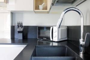 un comptoir de cuisine avec un micro-ondes et un évier dans l'établissement CASA YARA - appartamento moderno, Dolomiti Affitti, à Cavalese