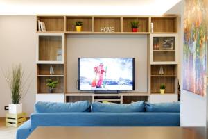 un salon avec un canapé bleu et une télévision dans l'établissement CASA YARA - appartamento moderno, Dolomiti Affitti, à Cavalese 34 autres photos
