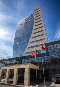 a tall building with flags in front of it at Moncher Hotel in Tuzla