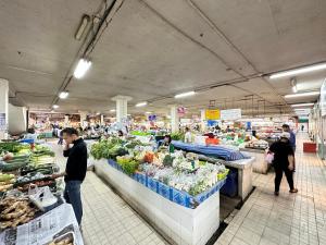 eine Gruppe von Menschen auf einem Markt mit Obst und Gemüse in der Unterkunft Comfy Boutique House in Chiang Mai