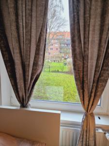 een raam met gordijnen en uitzicht op een groen veld bij Full Apartment in Hamburg-Mitte in Hamburg