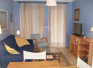 a living room with a blue couch and a tv at BAJO EN COSTA GADIR in Chiclana de la Frontera