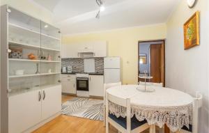 a kitchen with white cabinets and a table at Nice Apartment In Stara Baska 1 With Wifi in Stara Baška