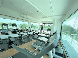 un gimnasio con cintas de correr, elípticas y ventanas en GEEN Hotel Chonburi en Chon Buri