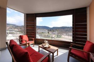 Cette chambre dispose d'une grande fenêtre avec des chaises et une table. dans l'établissement Le Panoramic - Vue exceptionnelle, à Gérardmer