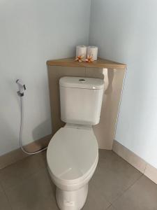 a bathroom with a toilet with a wooden shelf above it at Mojito Beach Villas in Kubutambahan