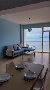 a living room with a couch and a table and chairs at Summer Breeze Apartment Saranda in Sarandë +9 photos