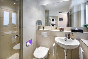 チューリッヒにあるアパルトホテル ファミリエ ヒューゲンシュミットのバスルーム(洗面台、トイレ、鏡付)