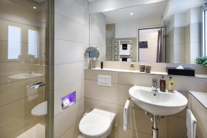 a bathroom with a sink and a toilet and a mirror at Aparthotel Familie Hugenschmidt in Zurich