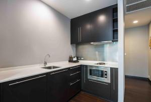 a kitchen with black cabinets and white counter tops at Chatrium Hotel Riverside Bangkok in Bangkok
