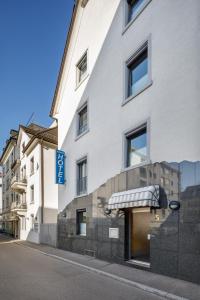 un bâtiment blanc avec un panneau bleu sur son côté dans l'établissement Aparthotel Familie Hugenschmidt, à Zurich