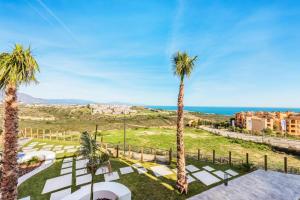 a view of a lawn with palm trees and the ocean at Small Oasis Nelson Mandela Apartment with sea view, two bedrooms, parking, terrace and pool in Manilva
