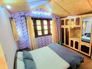 1 dormitorio con paredes moradas, 1 cama y ventana en Merlin Grove Suites Simla, en Shimla