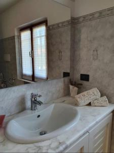een badkamer met een witte wastafel en een spiegel bij La Casa del Sole in Fresonara