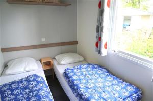 a small room with two beds and a window at CAMPING LES EMBRUNS 3* in Camoël