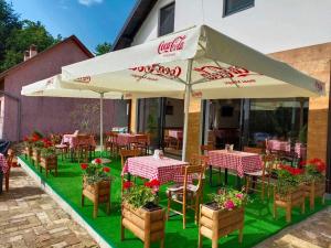 a restaurant with tables and chairs and umbrellas at Fruškogorski Đeram in Grgeteg
