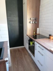 a kitchen with white cabinets and a black chalkboard at Books Apartments- blisko morza in Gdańsk