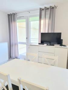 a living room with a television and a table and chairs at Apartamenty Bałtyk Park in Ustka