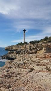 a lighthouse on top of a rocky island at Apartamentos Wundermar in Torredembarra