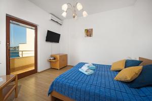ein Schlafzimmer mit einem blauen Bett und einem Balkon in der Unterkunft Apartments Kaina in Tisno