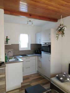 una cucina con elettrodomestici bianchi e soffitto in legno di Bungalow am Schwielochsee a Schwielochsee