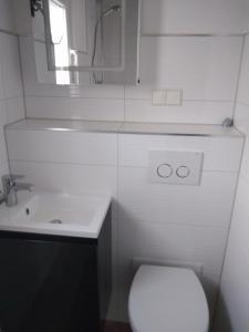een witte badkamer met een toilet en een wastafel bij Bungalow am Schwielochsee in Schwielochsee