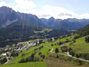 een groene vallei met een klein dorpje in de bergen bij Alvetern Tschuetta in Scuol