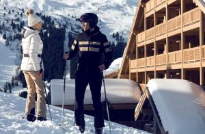 a man and a woman on skis in the snow at Antarès Méribel Resort & SPA in Les Allues