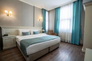 a bedroom with a large bed with blue curtains at Valide Hotel in Istanbul