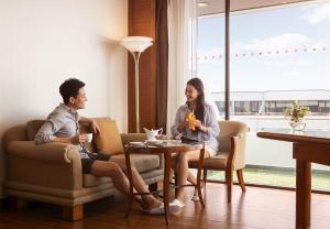 a man and woman sitting in chairs in a living room at Amari Don Muang Airport Bangkok in Bangkok