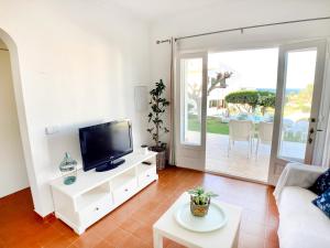 sala de estar con TV y sofá en La Casa del Jardin. Menorca en Punta Grossa