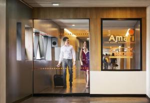 a man walking down a hallway with a woman with a suitcase at Amari Don Muang Airport Bangkok in Bangkok