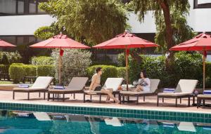 two people sitting in lounge chairs next to a pool at Amari Don Muang Airport Bangkok in Bangkok