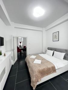 a white bedroom with a large bed and a desk at Cozy Aparthotel - Central City Suceava in Suceava