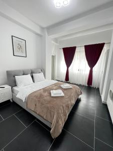 蘇恰瓦的住宿－Cozy Aparthotel - Central City Suceava，一间卧室配有一张带红色窗帘的大床