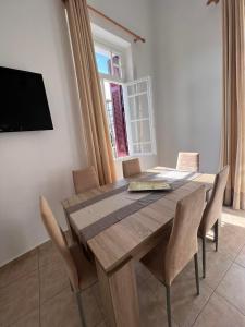 a dining room table with chairs and a flat screen tv at Tinos Central Perfection in Tinos