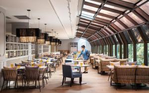 a dining room with tables and a man standing in the middle at Amari Don Muang Airport Bangkok in Bangkok