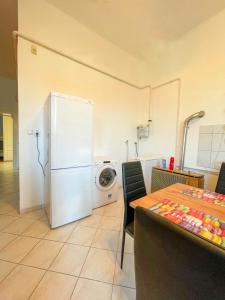 a kitchen with a white refrigerator and a table with chairs at Centrum Hostel in Pécs